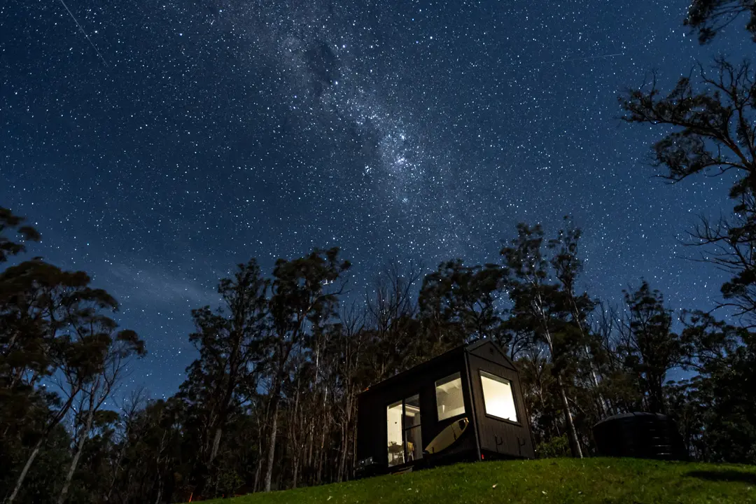 Tiny house at night with starry night sky.